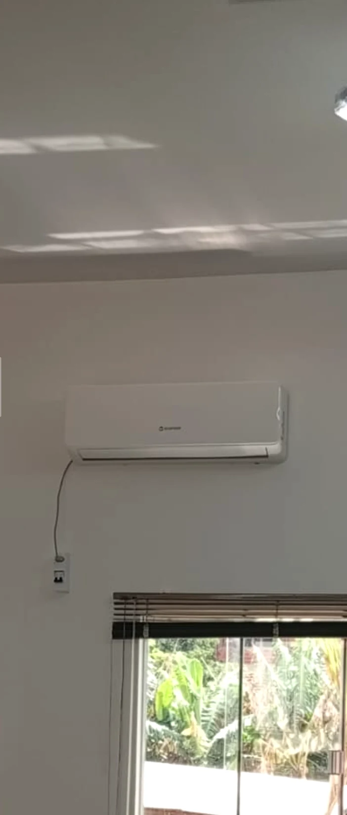 Unidade interna Split Hi-Wall instalada em ambiente residencial, acima de uma janela