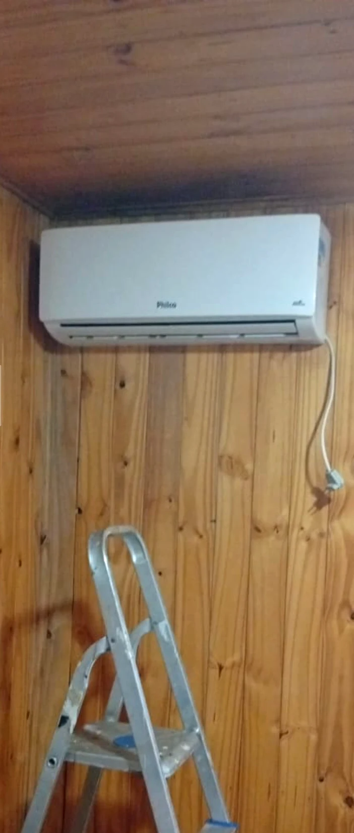 Unidade interna Split instalada em parede de madeira, com escada no ambiente